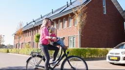 Vrouw fiets door wijk met zonnepanelen